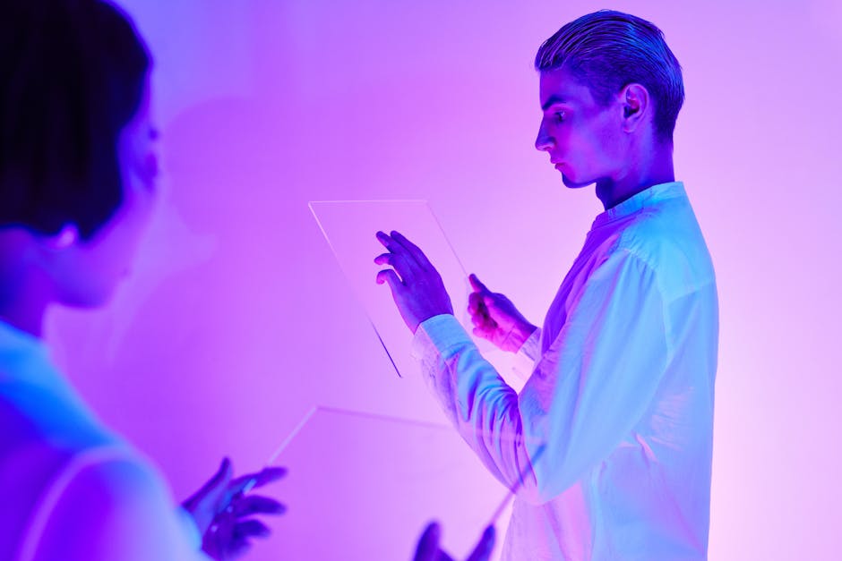 Two individuals engaging with futuristic transparent touch screens in a vibrant purple-lit studio